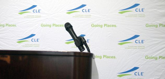 Microphone and Lectern in front of a CLE branded backdrop